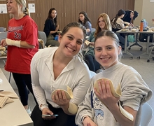 Two young people hold items in their hands while sitting in a classroom