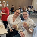 Two young people hold items in their hands while sitting in a classroom